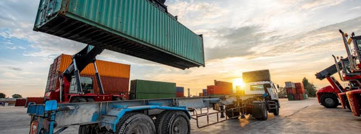 Shipping containers being moved at sunset